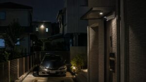 夜の駐車場と車を屋外防犯カメラで見守る住宅の外観