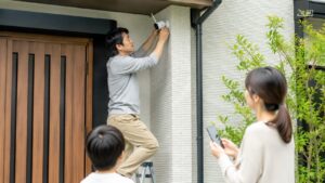 家族で見守りながら屋外用防犯カメラを取り付ける日本人男性