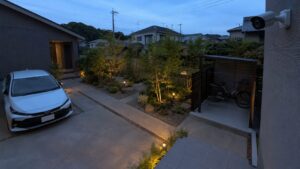夕方の駐車場と庭を広く見守る外壁設置の屋外防犯カメラ