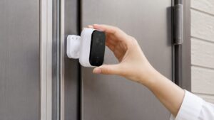 金属製の玄関ドアにマグネット式防犯カメラを取り付ける様子