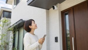 工事不要の屋外防犯カメラを玄関に設置し、スマホで確認する日本人女性